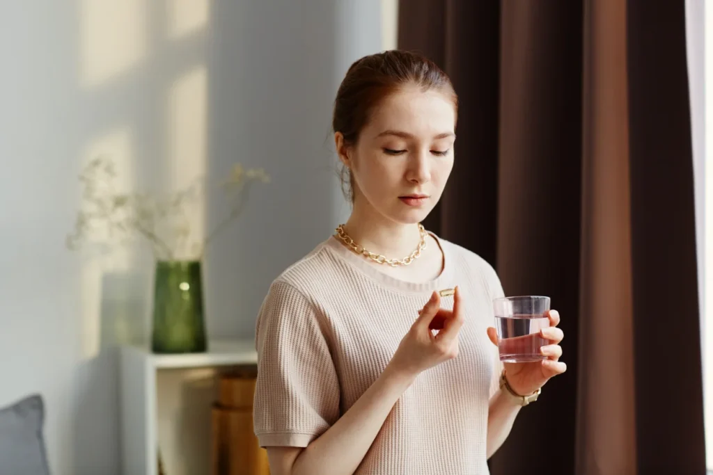 Lady taking a pill with a glass of water