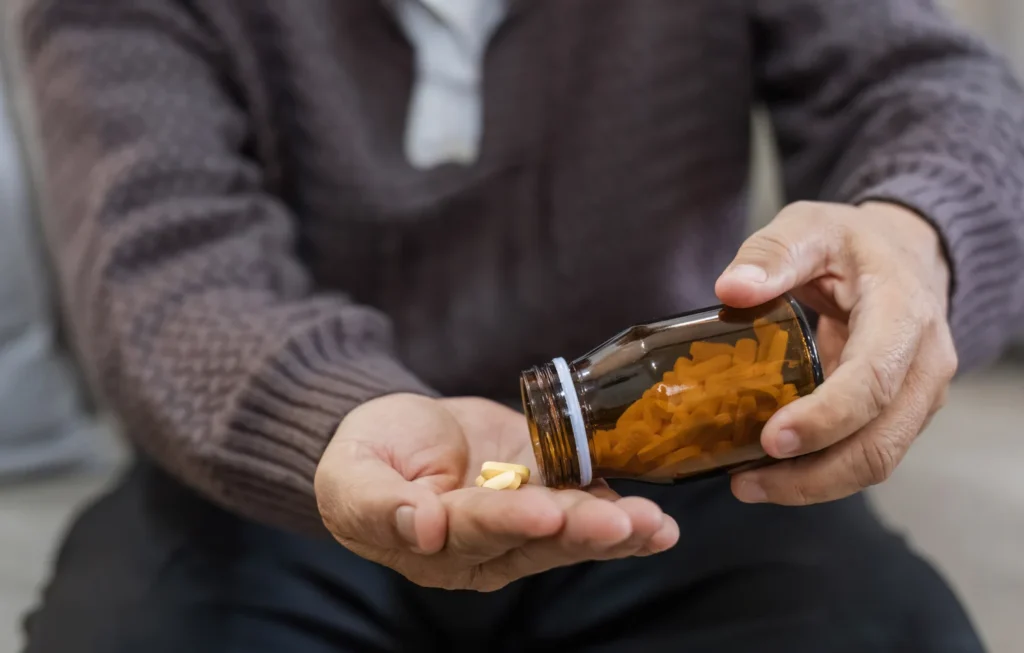 A man taking a supplement pill out of a bottle