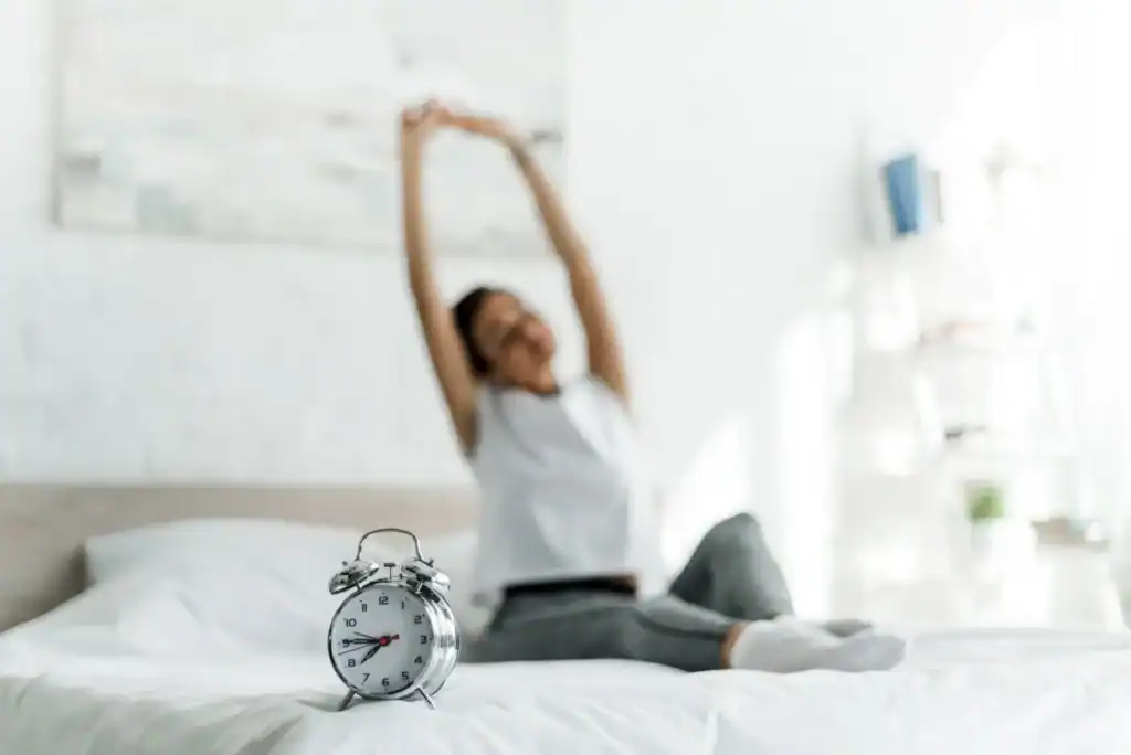 selective-focus-of-woman-stretching-with-alarm-clock