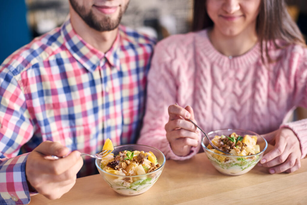 Uomo e donna che pranzano con un'insalata, alimento salutare e bilanciato.