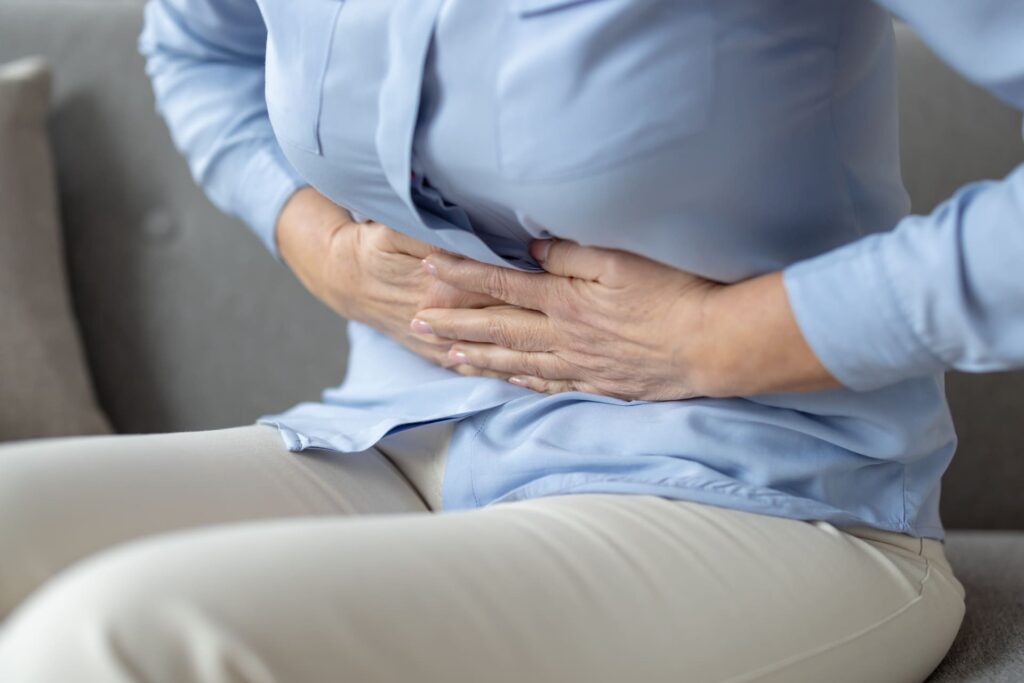 Donna con difficoltà di digestione che si regge la zona dello stomaco.