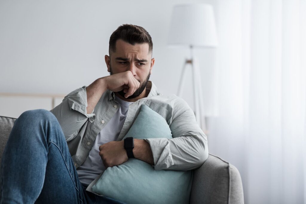 Uomo che prova forte senso di nausea seduto.