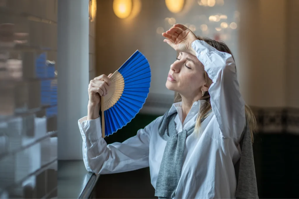 Donna in menopausa che si sventola con un ventaglio a causa delle vampate di calore