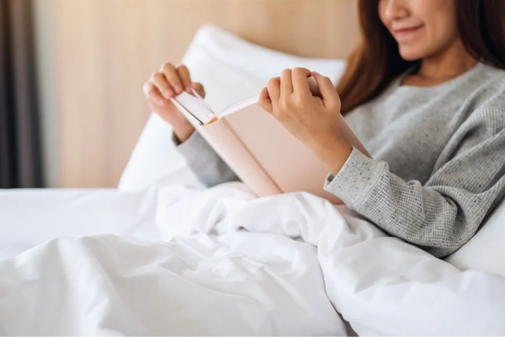 Giovane donna che legge un libro a letto