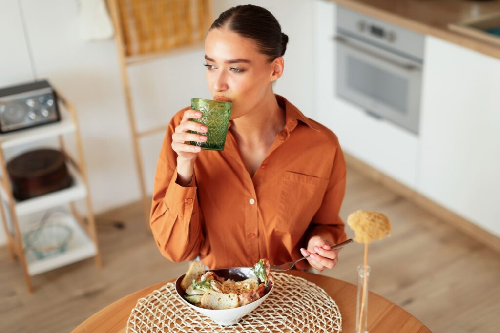 Donna che pranza con insalata e acqua.