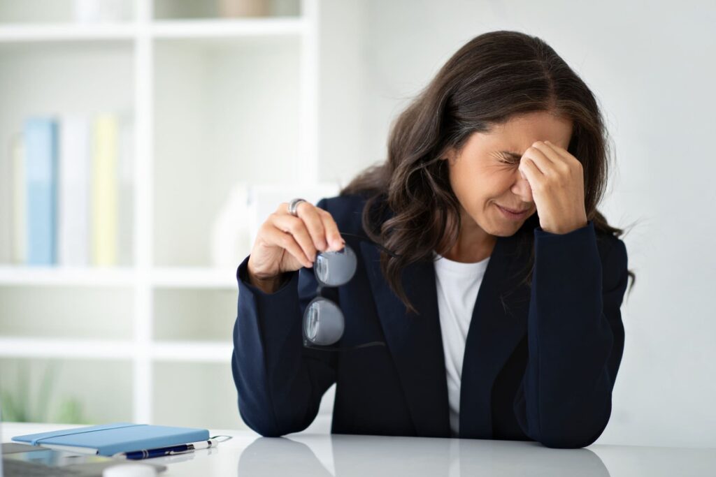 Donna al lavoro che si tocca occhi e fronte a causa di un forte momento di stress.