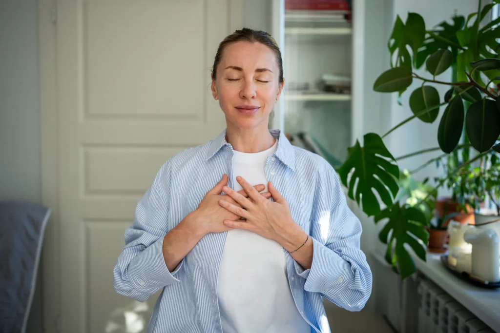 Donna che pratica respiri profondi a occhi chiusi e con le mani sul petto