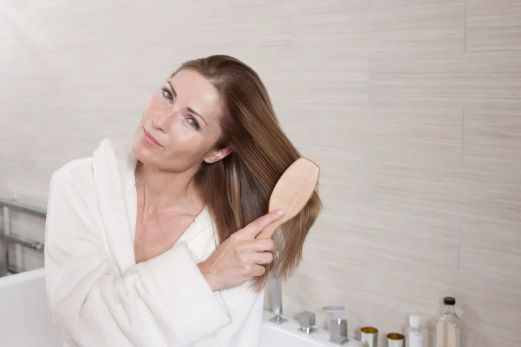 Donna matura si spazzola i capelli in bagno