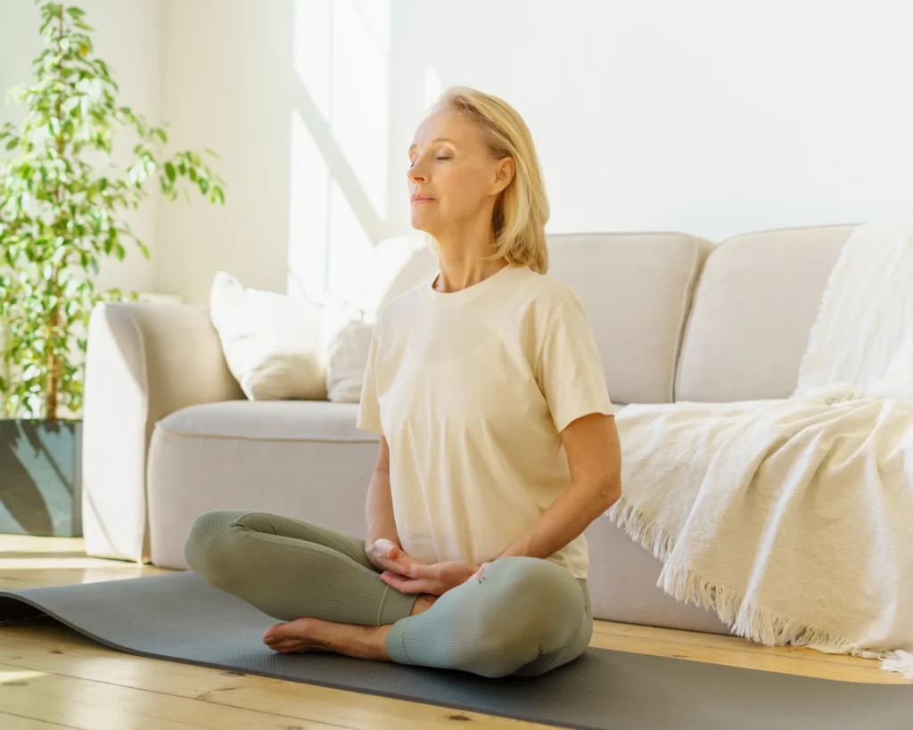 Donna fa yoga in casa con le gambe incrociate e gli occhi chiusi