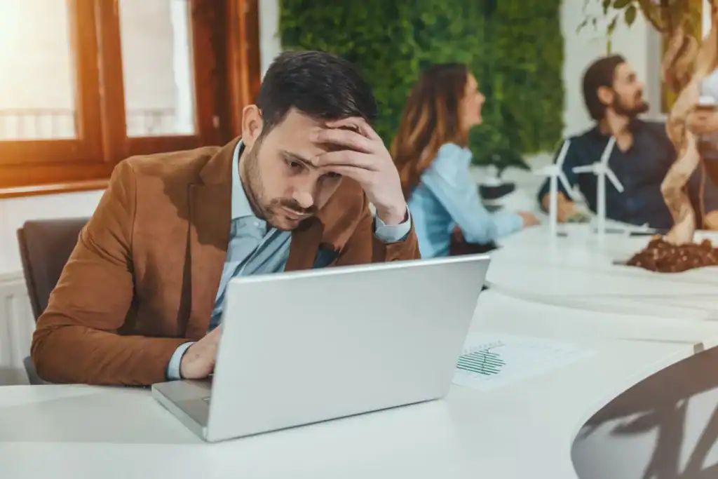 Uomo molto stanco che lavora al computer portatile
