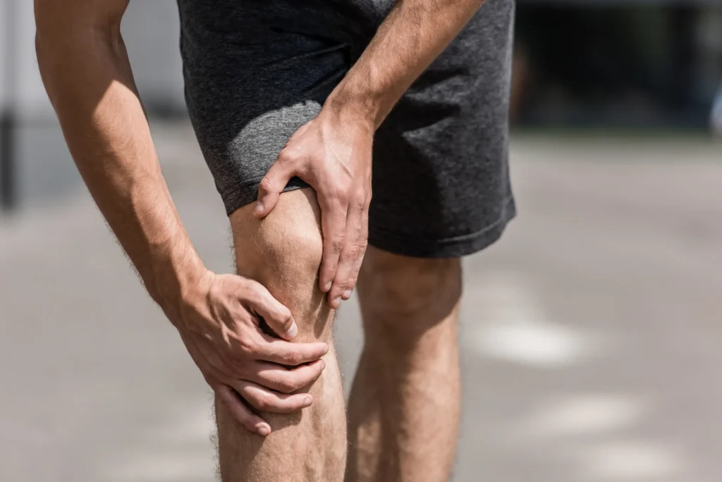 Un uomo che indossa dei pantaloncini corti si tocca il ginocchio