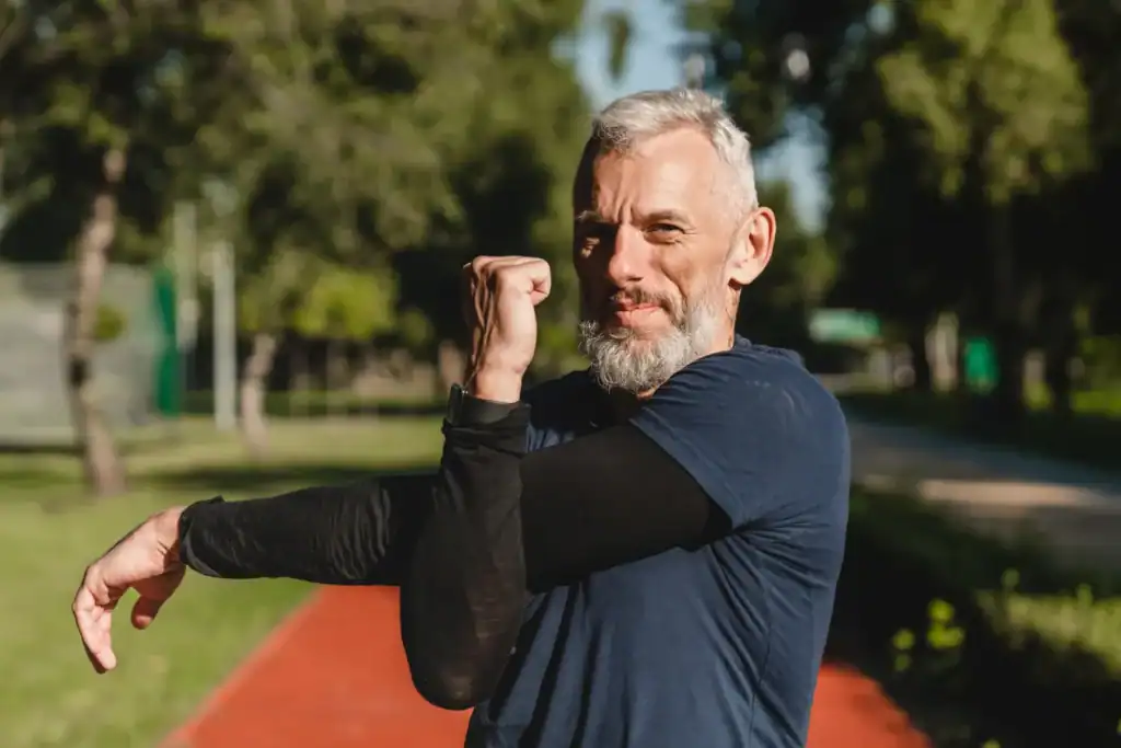 Inquadratura parziale di un atleta che fa stretching alle braccia prima di un allenamento di corsa all'aperto nello stadio.
