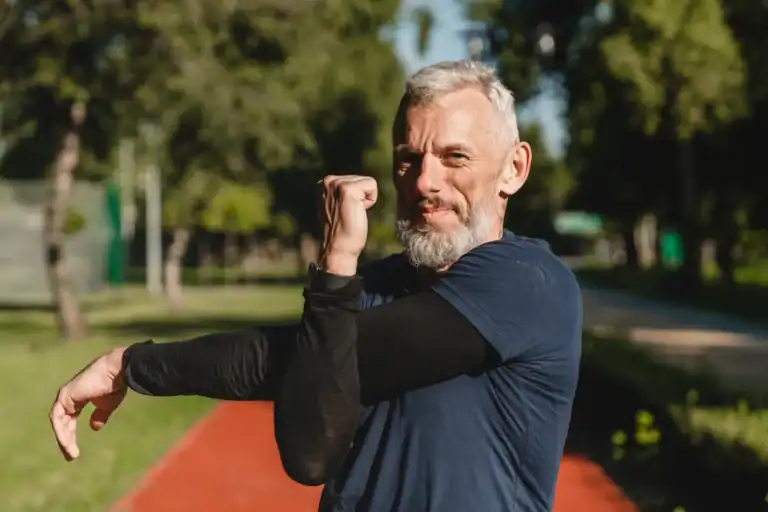 Inquadratura parziale di un atleta che fa stretching alle braccia prima di un allenamento di corsa all'aperto nello stadio.