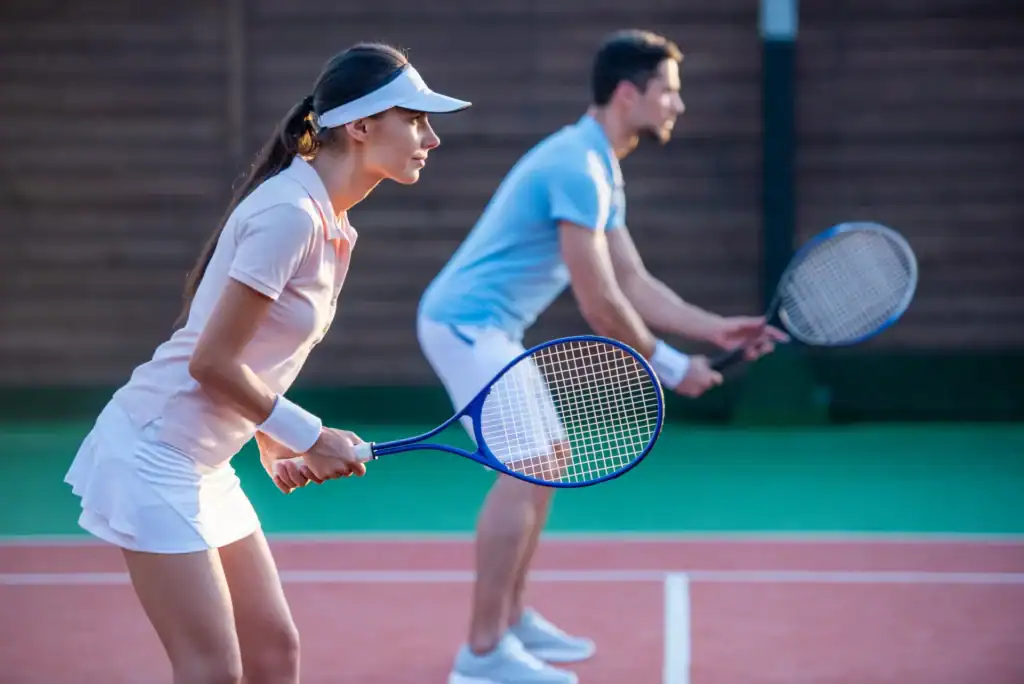 Un uomo e una donna giocano a tennis insieme su un campo.