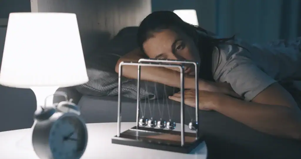 Donna insonne a letto con il pendolo di Newton