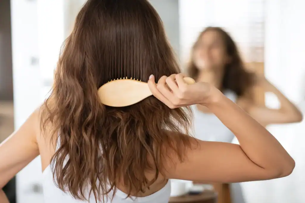 Donna che si spazzola i capelli in bagno