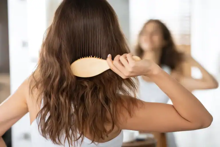 Donna che si spazzola i capelli in bagno