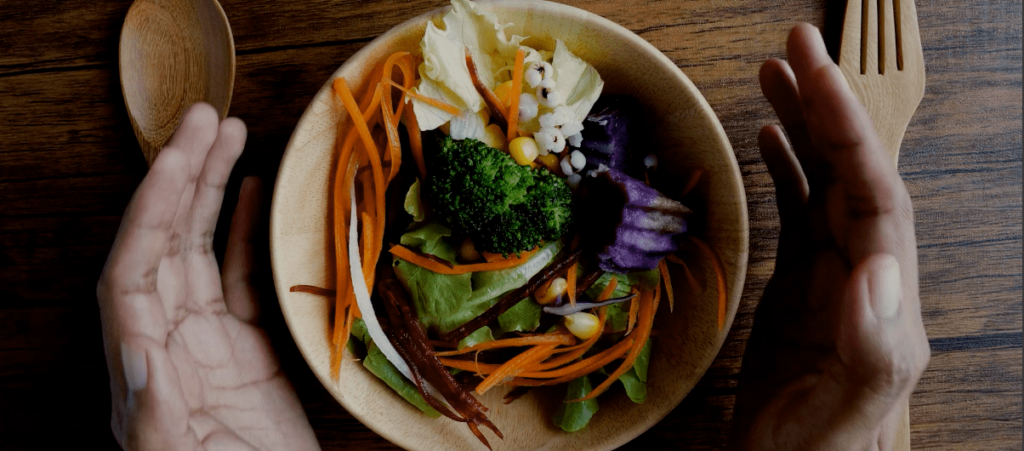 Piatto di verdure circondato da due mani
