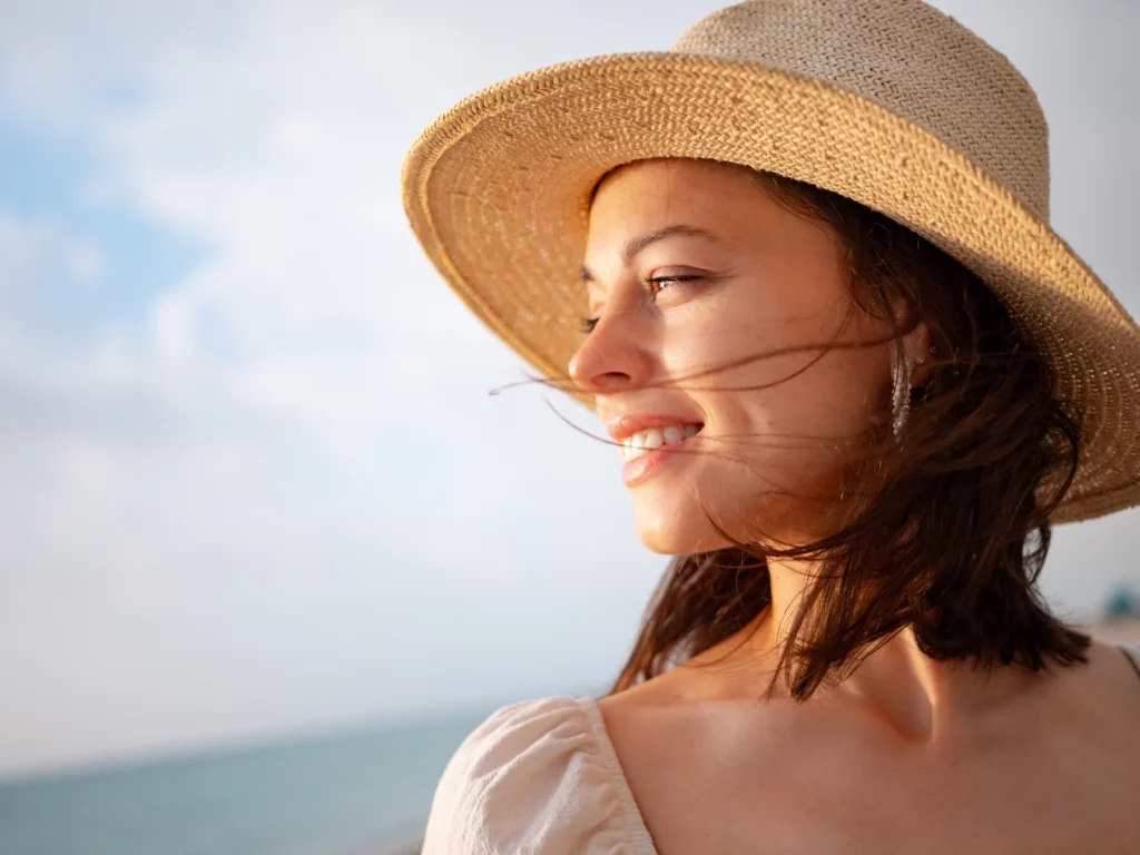 giovane ragazza con il vento in faccia con cappello di paglia baciata dal sole che fa la ricarica di vitamina D